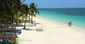 plage de sable blanc aux eaux turquoise avec bateaux de pêche et palmiers, cayo ensenacho cuba