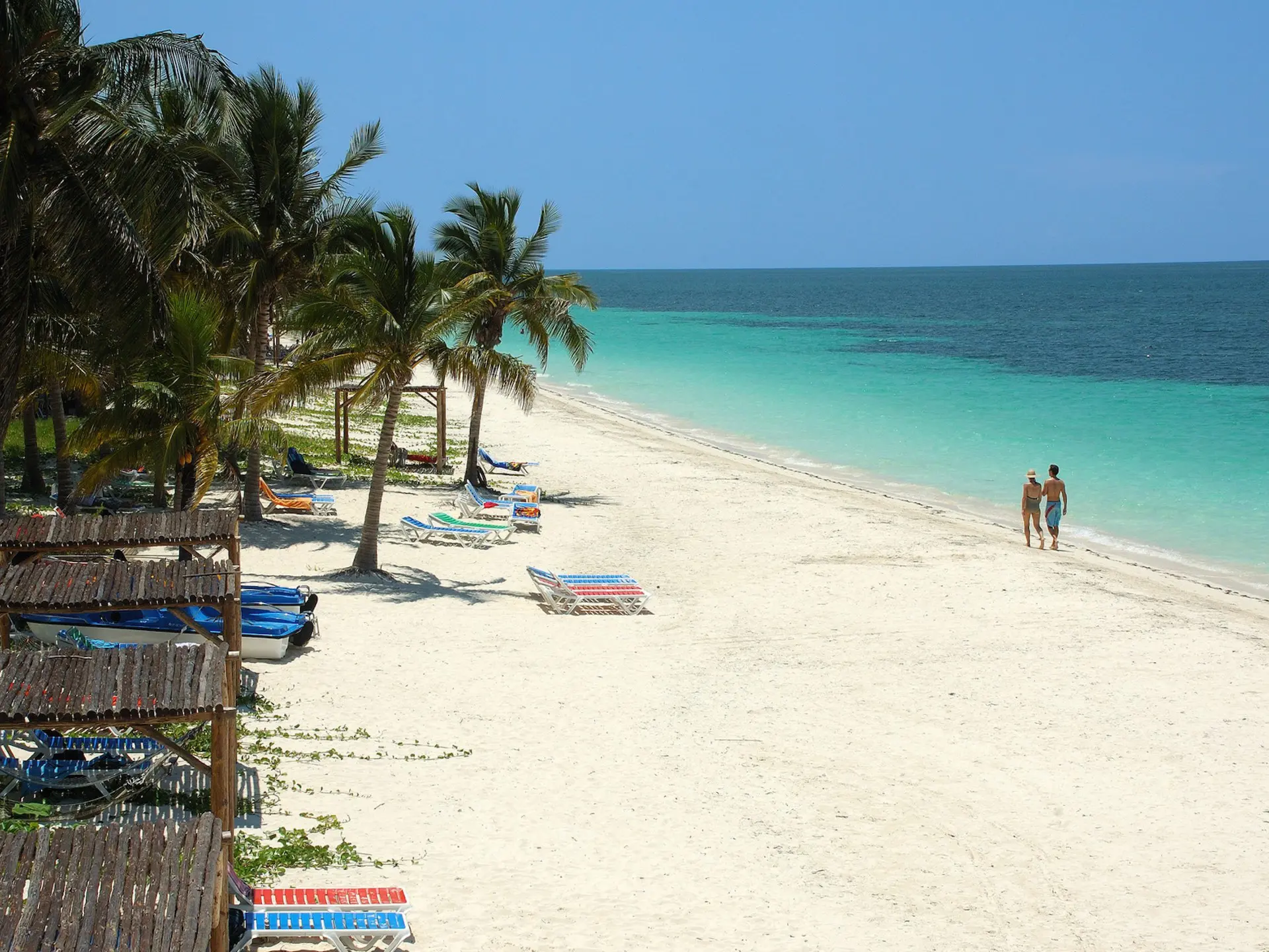 plage de sable blanc aux eaux turquoise avec bateaux de pêche et palmiers, cayo ensenacho cuba
