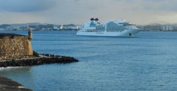 White cruise ship near historic San Juan fort, Puerto Rico at sunset.