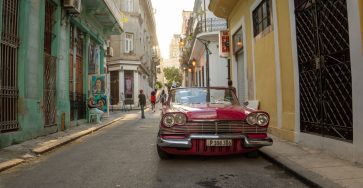 A classic car parked on a lively street in Havana, Cuba, capturing the essence of local culture and architecture.