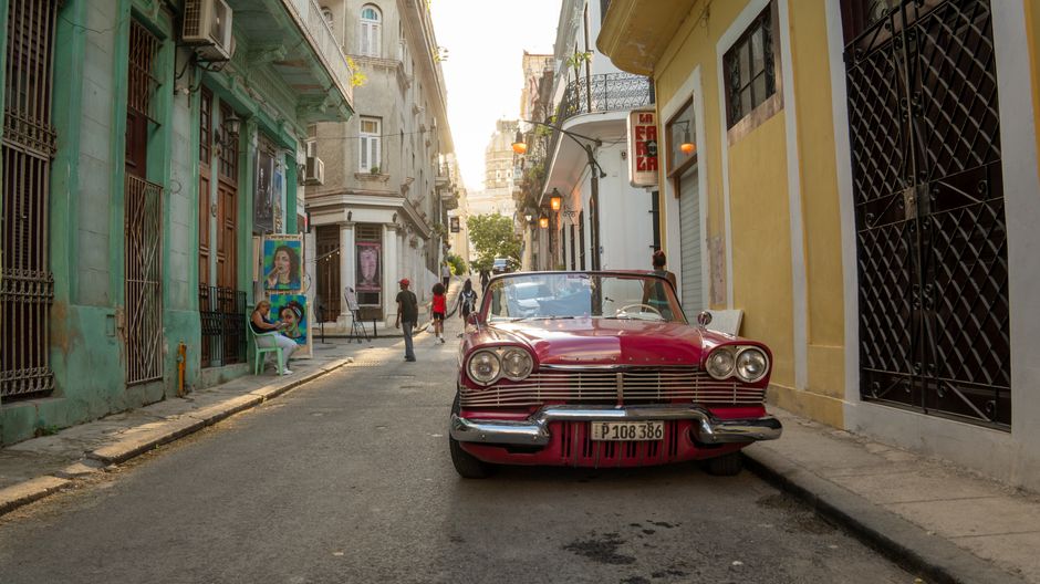 A classic car parked on a lively street in Havana, Cuba, capturing the essence of local culture and architecture.