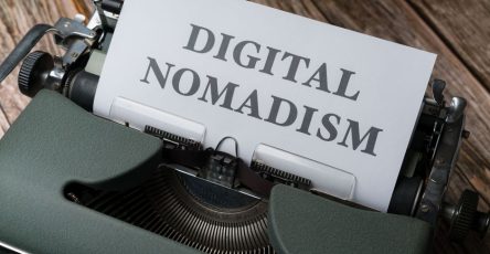 A classic typewriter with a paper reading 'Digital Nomadism' on a wooden desk.