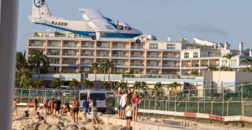 A plane flies low over tourists at Maho Beach, Sint Maarten, near the airport.