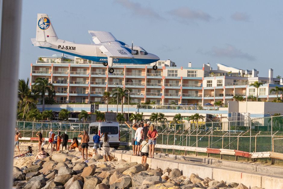 A plane flies low over tourists at Maho Beach, Sint Maarten, near the airport.